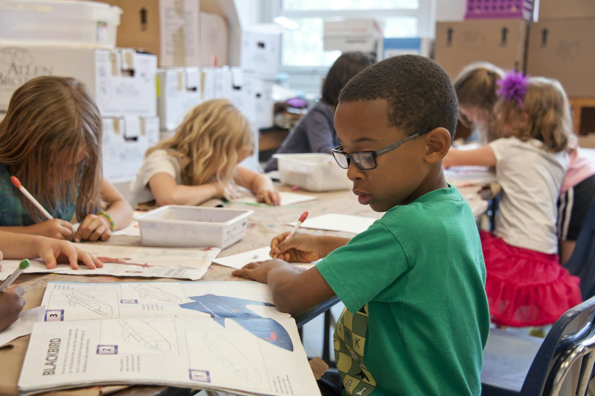 Children reading, writing, and learning together in a bright classroom.